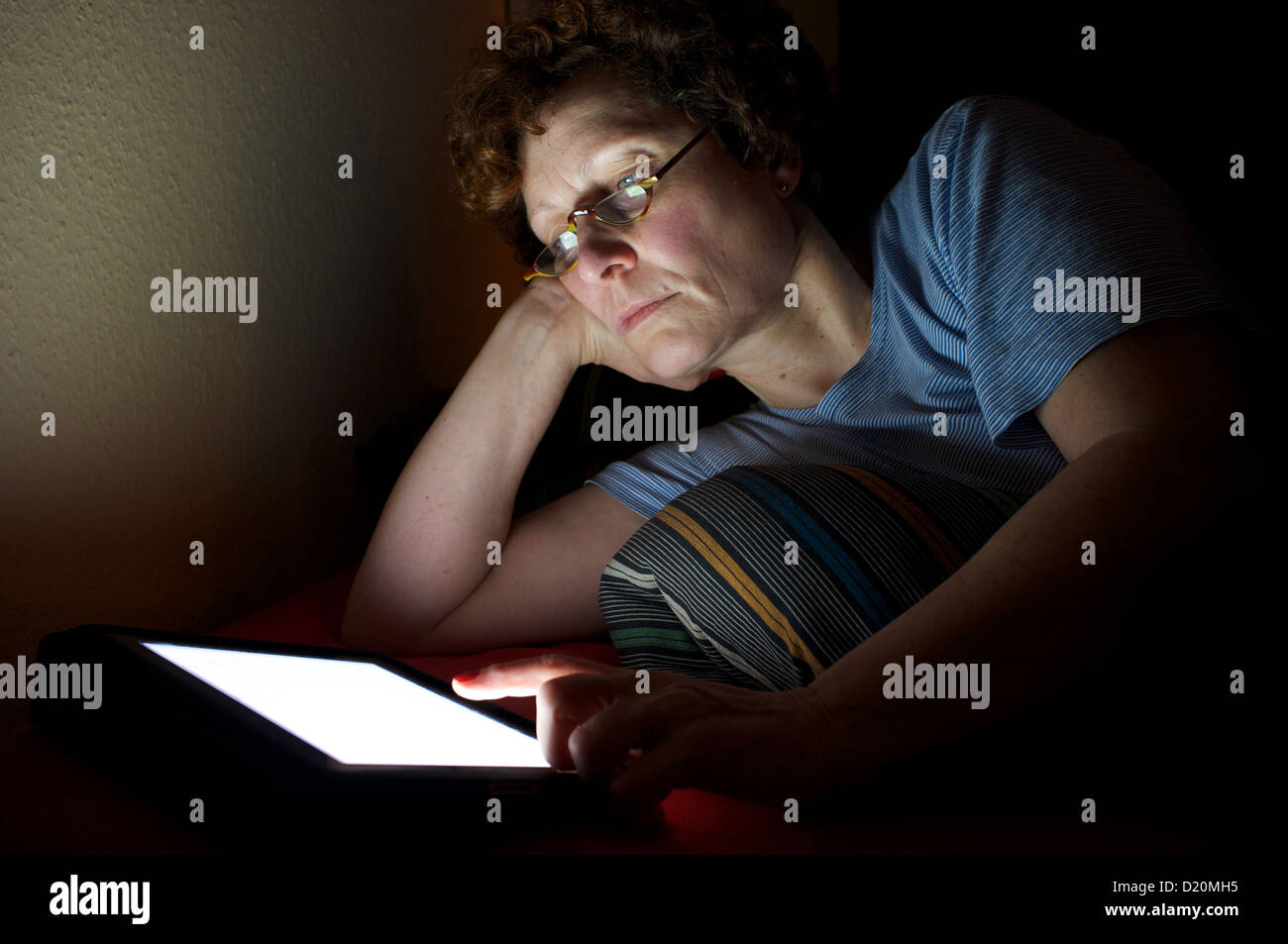 Frau liest ein Buch über ein e-Reader im Bett Stockfoto