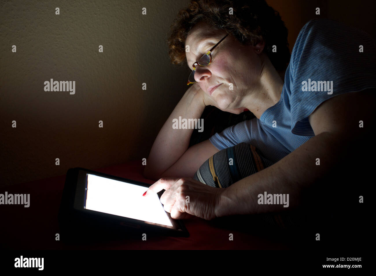 Frau liest ein Buch über ein e-Reader im Bett Stockfoto