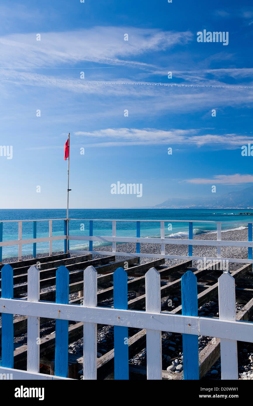 Eine rote Fahne auf einer Hecke an einem Strand Stockfoto