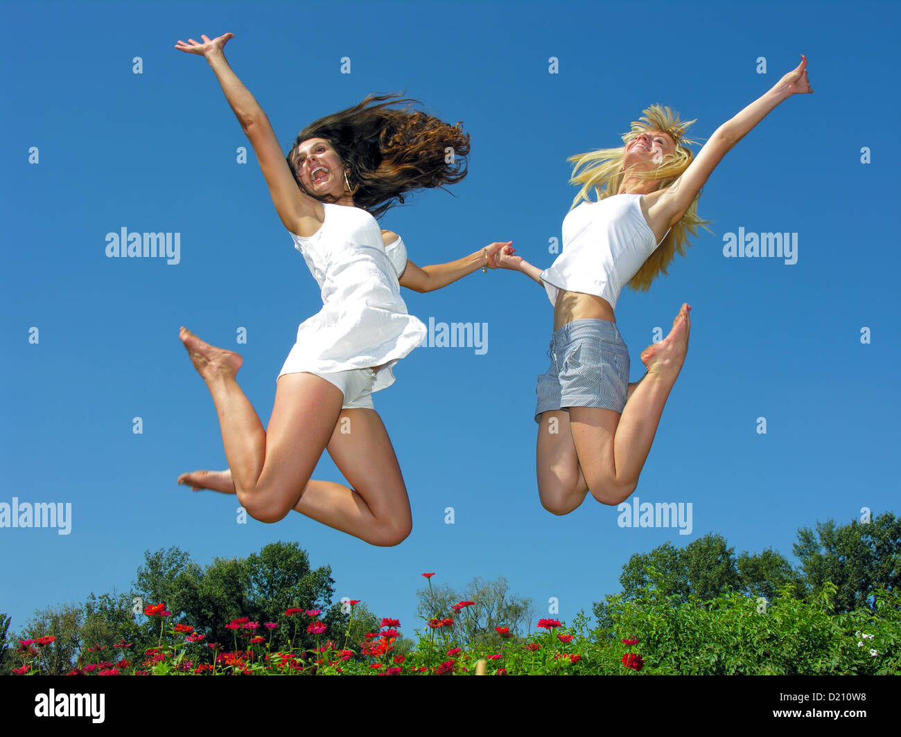 zwei fröhliche Freundinnen springen im freien Stockfoto