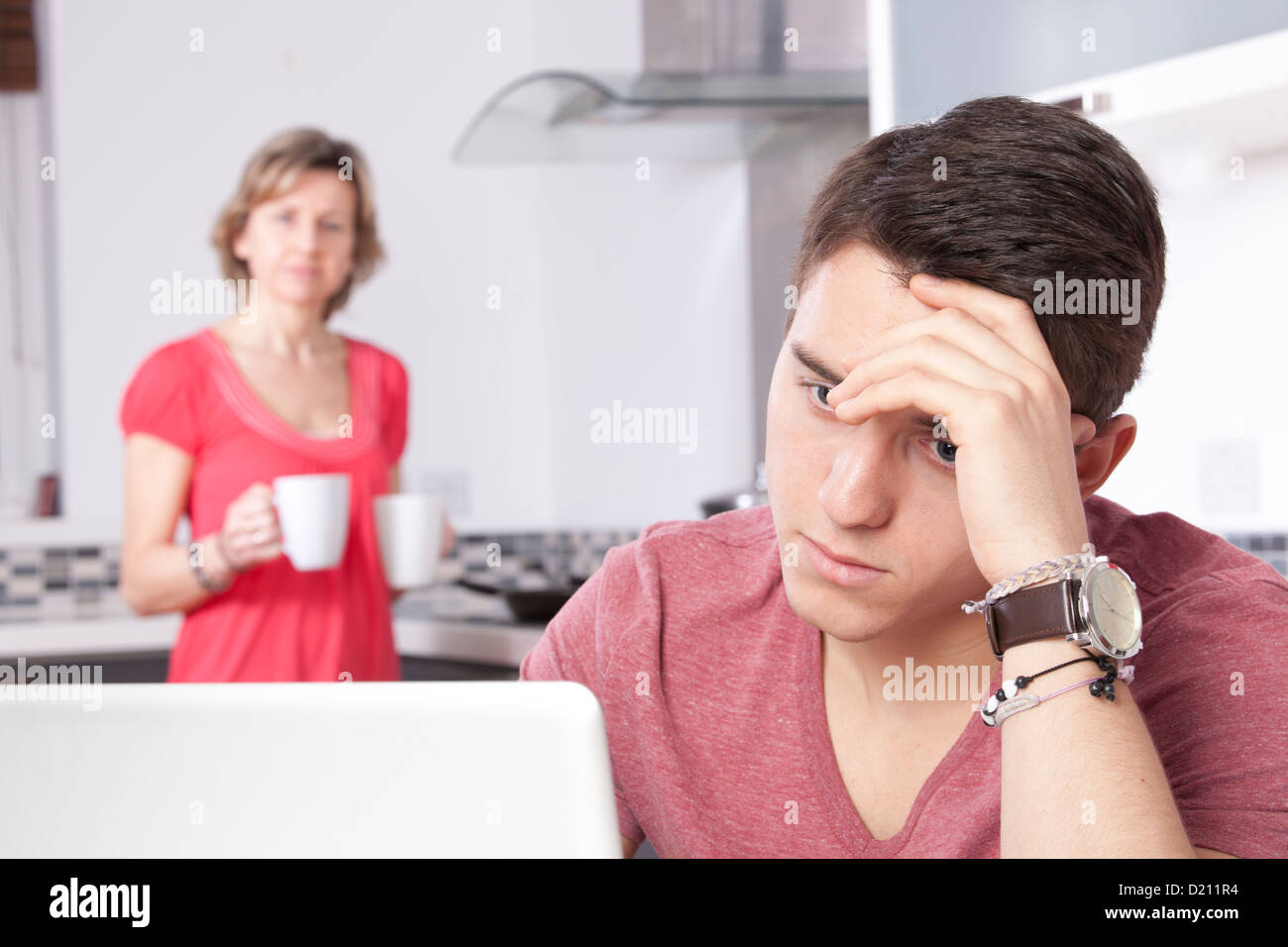 Worri Mann mit einem digitalen Tablet-Bildschirm oder Monitor zu betrachten. In einer modernen Küche sieht eine Frau mit 2 Tassen Buchungsänderungen Stockfoto