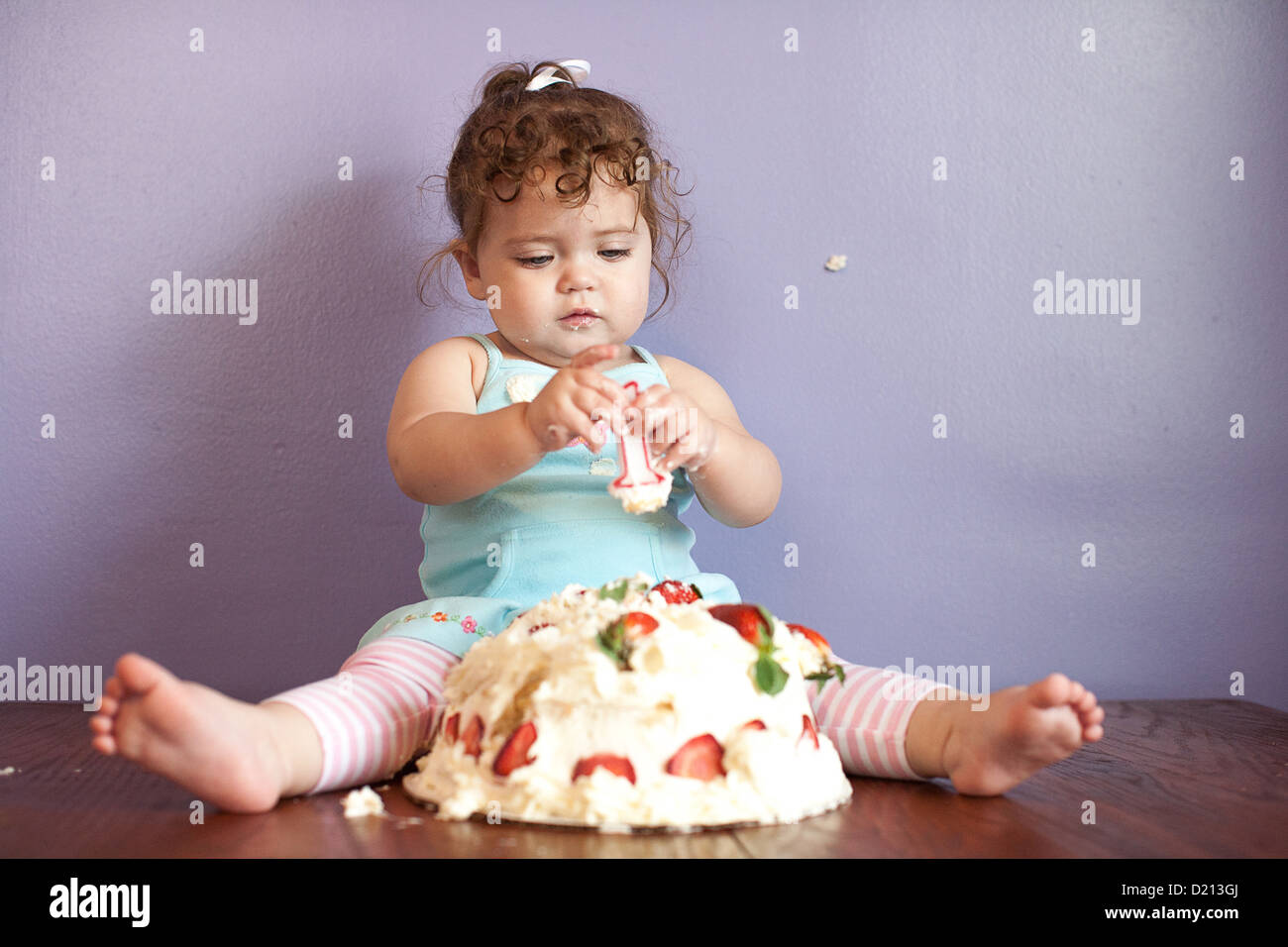 Niedlichen Mädchen spielen mit einem Geburtstagskuchen und Nummer eins Kerze. Stockfoto