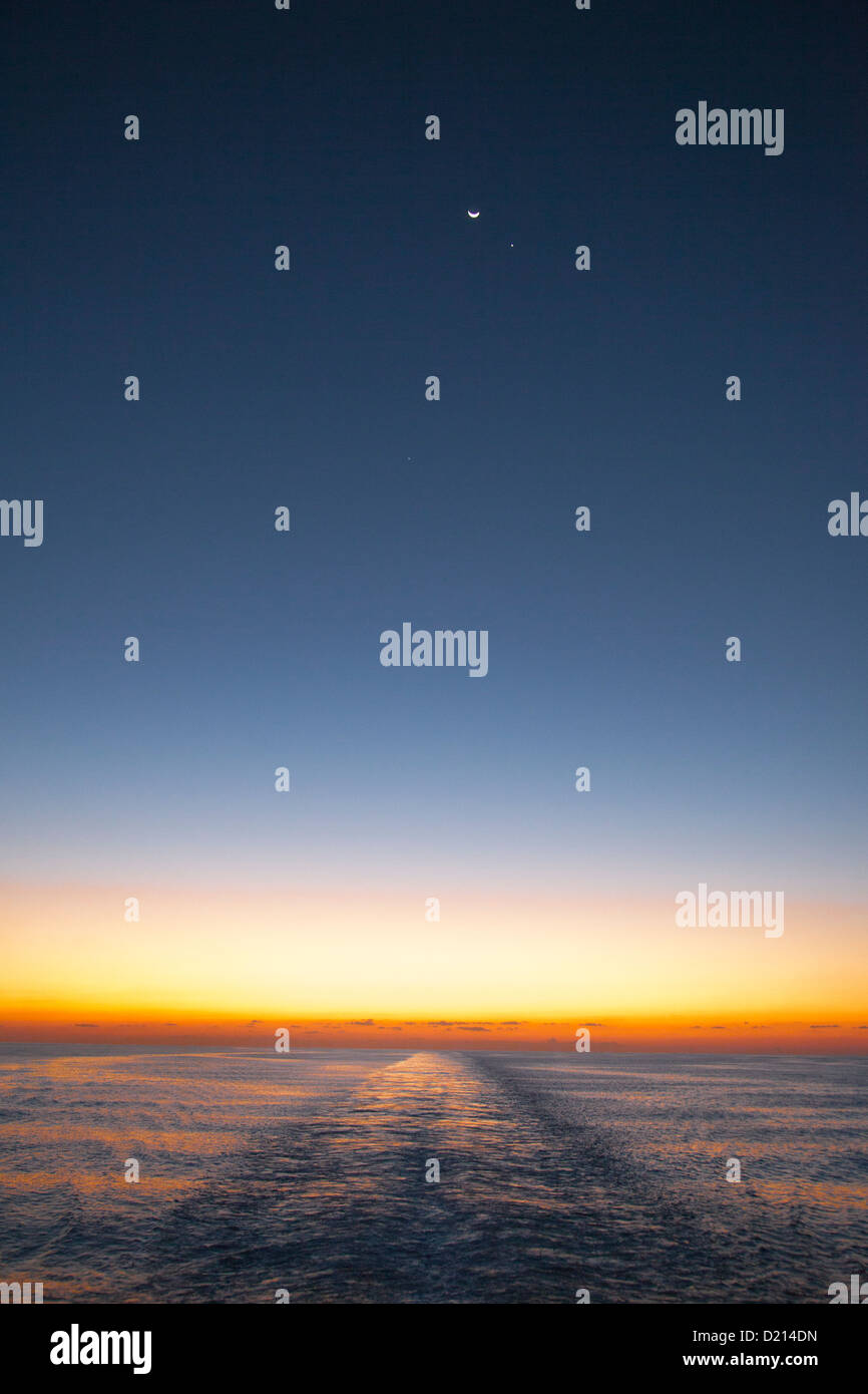 Horizont in der Abenddämmerung mit Mond, Planeten und Gefolge vom Kreuzfahrtschiff MS Deutschland (Reederei Peter Deilmann), Karibik, nahe C Stockfoto