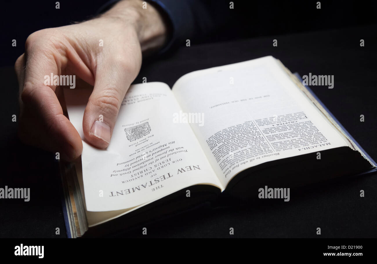 Ein Mann liest die Bibel mit einer Hand. Stockfoto