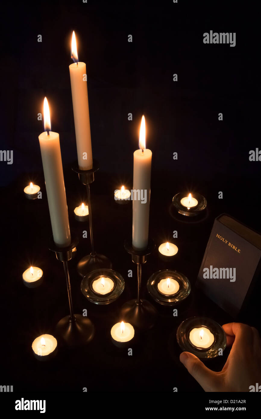 Eine Hand, die Kerzen auf dem Altar platziert Stockfoto