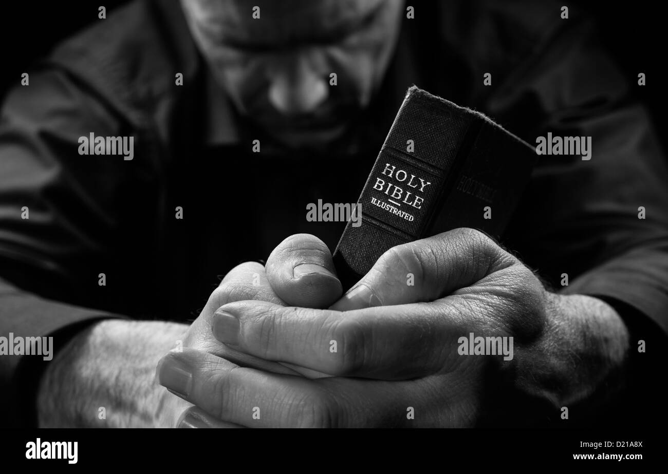 Das Bild von einem Mann, der betet, hält eine Bibel. Stockfoto