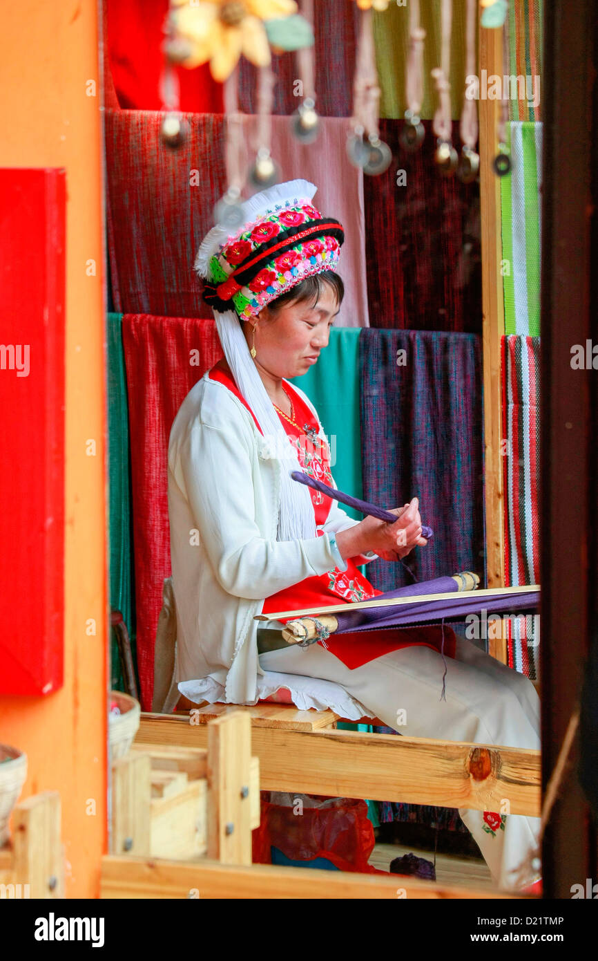 Porträt einer traditionellen Bai Frau weben, reflektiert im Spiegel der ihr Geschäft in Dali, Provinz Yunnan, Süd-West-China. Stockfoto