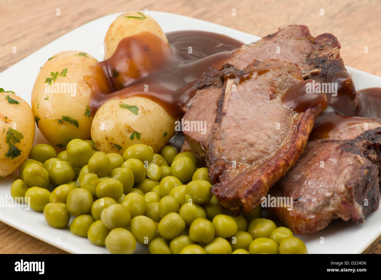 Lammkoteletts mit Erbsen, Kartoffeln und Soße - Studio mit einer geringen Schärfentiefe erschossen Stockfoto