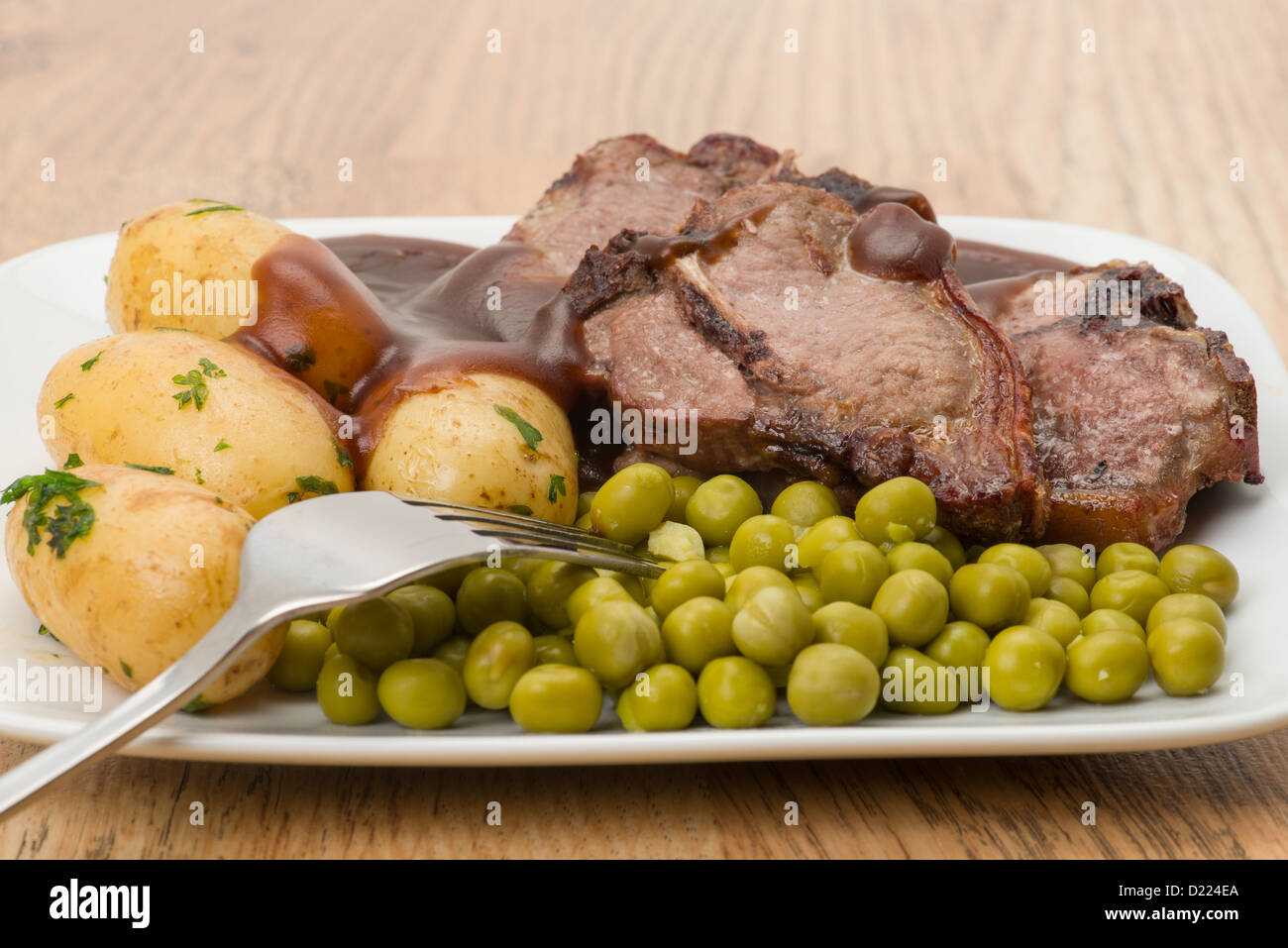 Lammkoteletts mit Erbsen, Kartoffeln und Soße - Studio gedreht Stockfoto