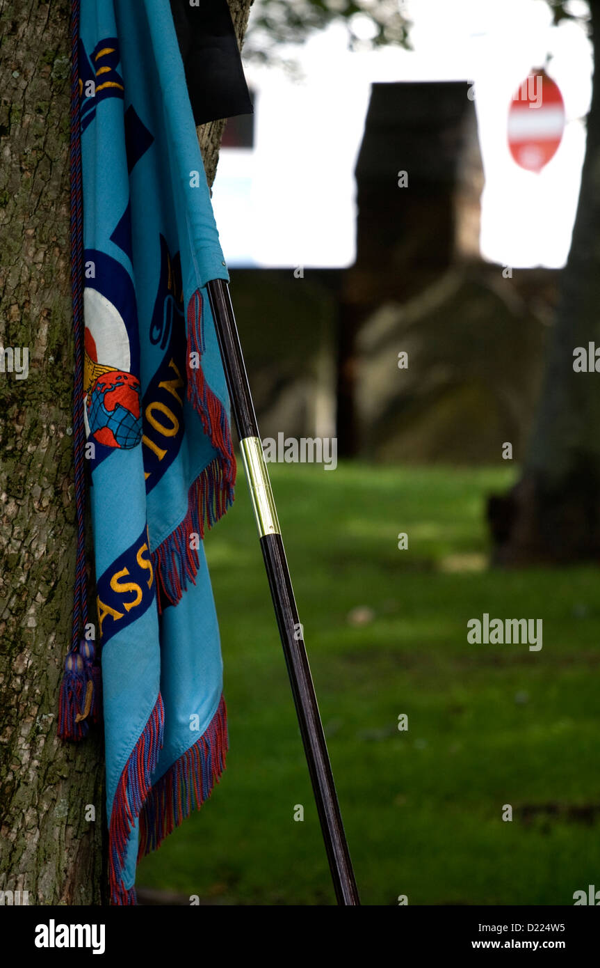 Militärische Flagge links Neigung gegen einen Baum auf einer Beerdigung. Stockfoto