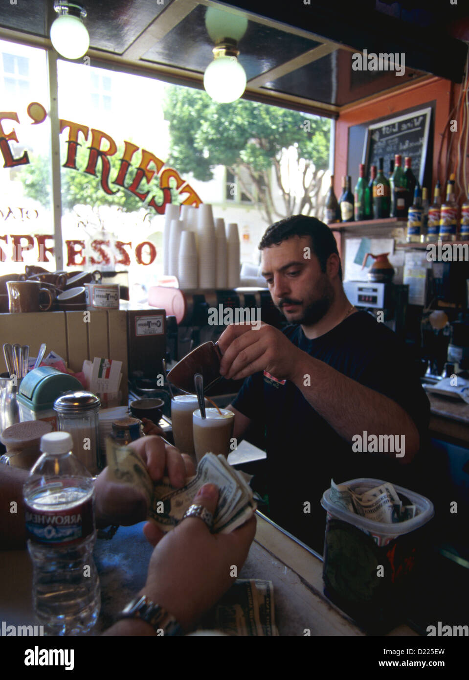 Barista ergießt Kaffee in Kaffee Latte Glas, wie Kunde zahlt und Geld in das Tipp-Glas bringt Stockfoto