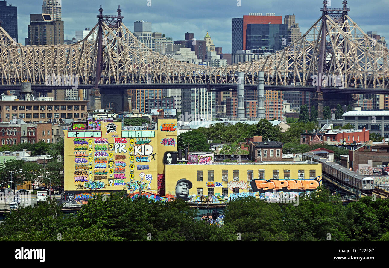 5 Pointz Graffiti-Museum mit der 59th Street Bridge und Manhattan Skyline im Hintergrund und der u-Bahn im Vordergrund. Stockfoto