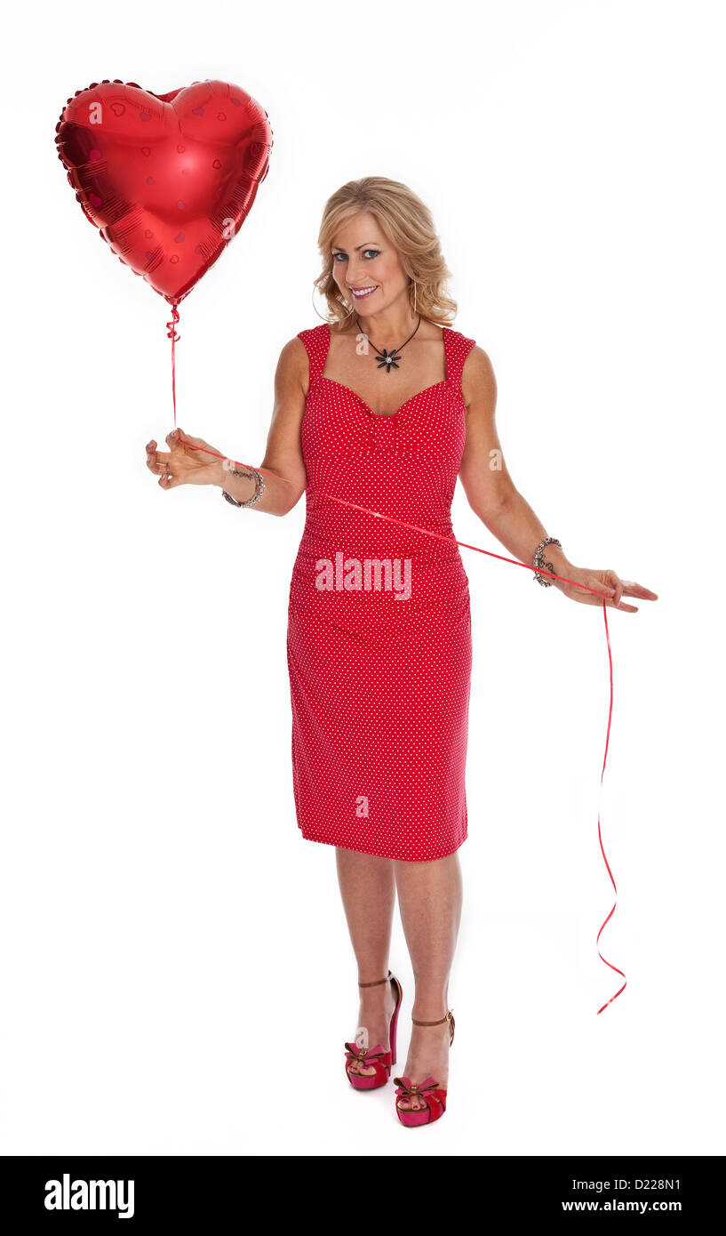 Voller Länge Foto 40 Jahre alten Frau im roten Kleid hält Herz geformten roten Ballon auf weißem Hintergrund. Stockfoto