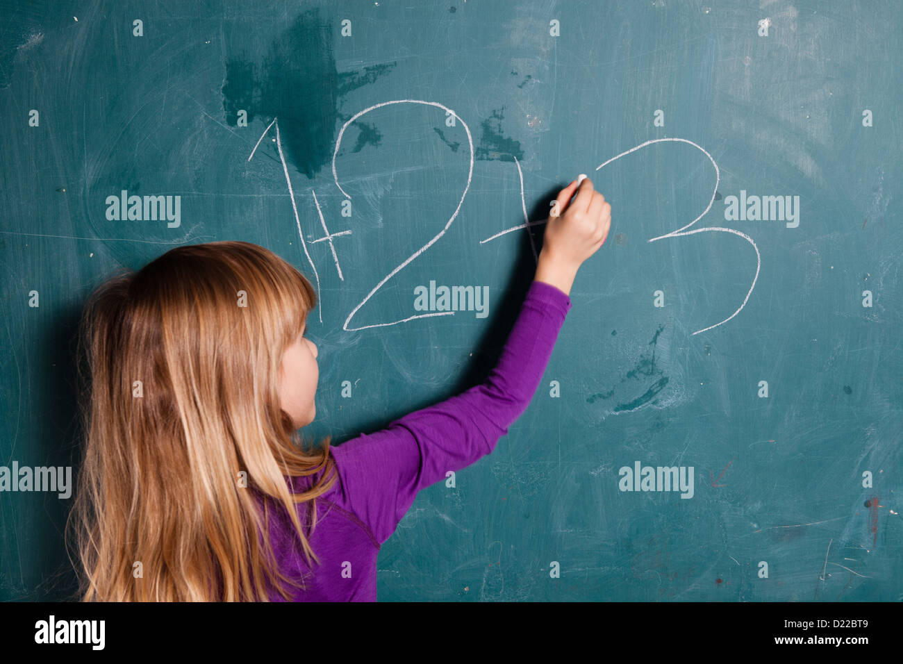 Junges Mädchen Zahlen auf Tafel mit Kreide zu schreiben Stockfoto