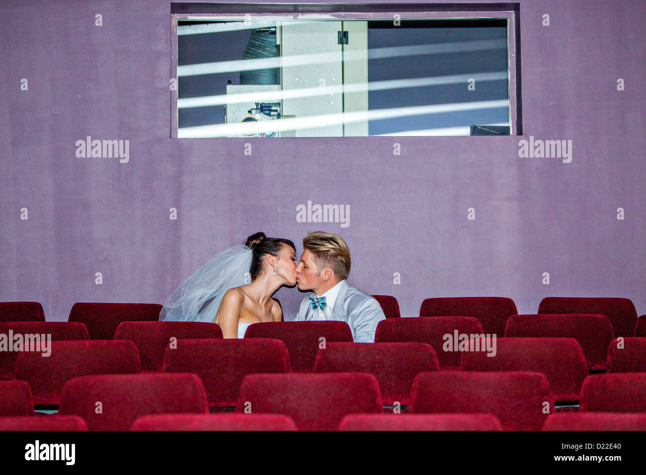 Junges Paar küssen im Kino am Tag ihrer Hochzeit Stockfoto