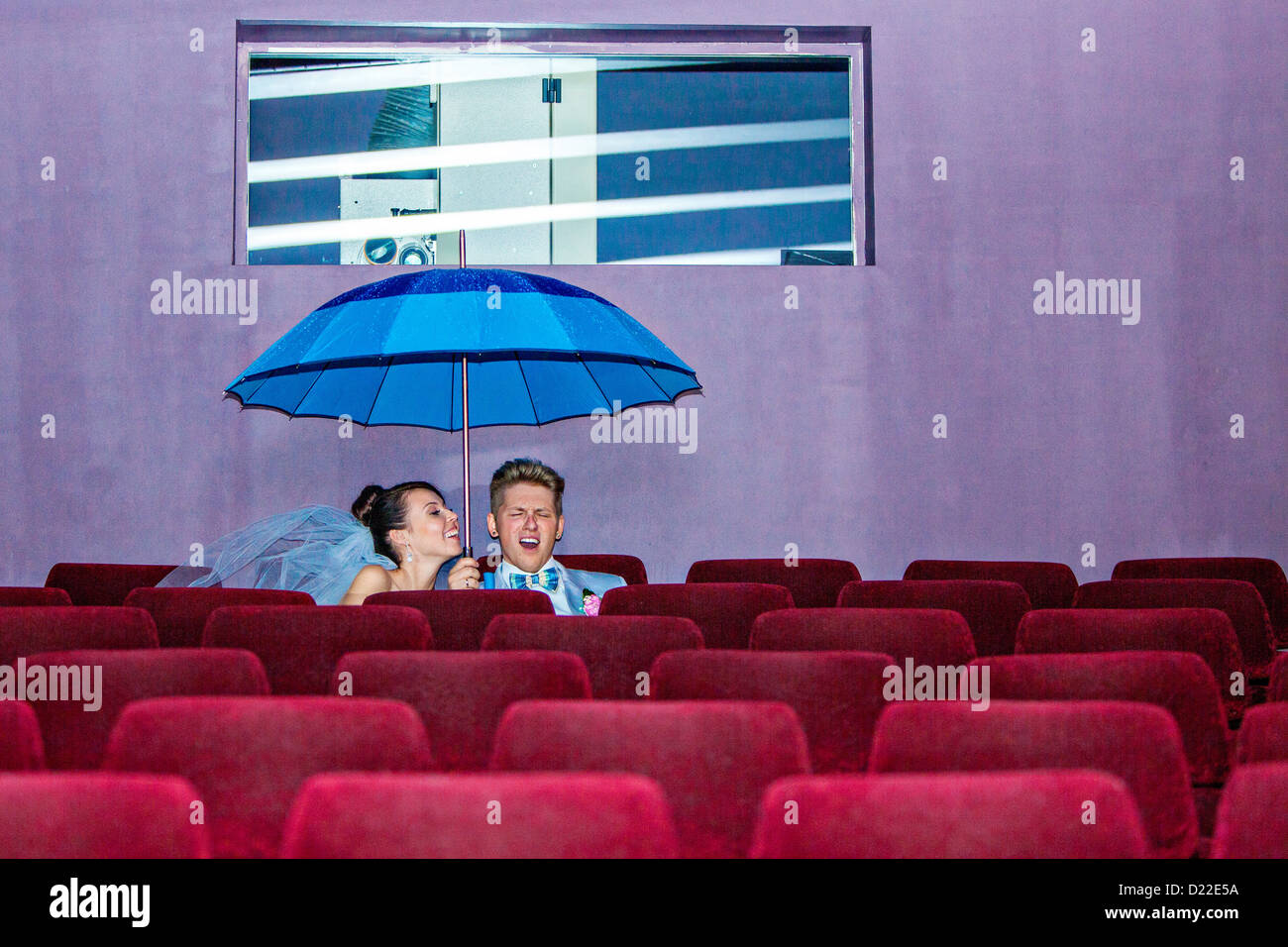 Junges Paar sitzt unter einem Dach im Kino am Tag ihrer Hochzeit Stockfoto