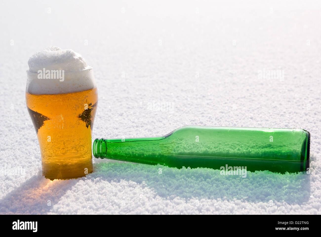 Bier im Glas und grüne Flasche auf Schnee Stockfoto