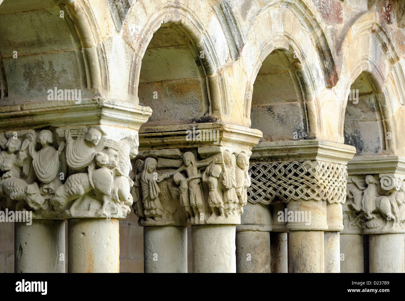 Intracately geschnitzte Kapitelle auf Säulen, die Bögen dieser Form Kolonnade des romanischen Colegiata Santillana del Mar Stockfoto