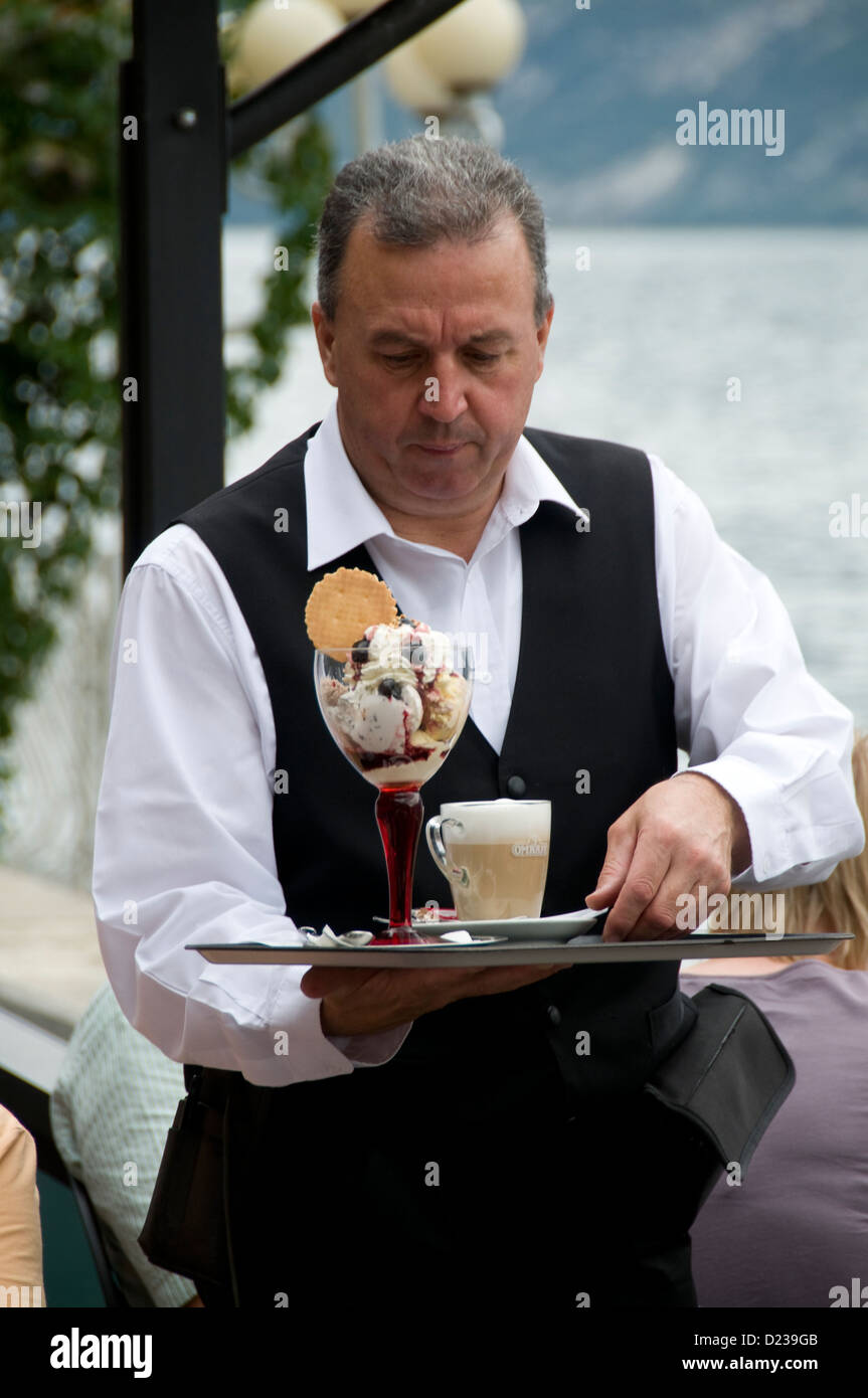 Ein Kellner serviert italienisches Eis und eine Tasse Kaffee in einem Restaurant in Limone Sul Garda am Gardasee in der Provinz Brescia in Norditalien. Stockfoto