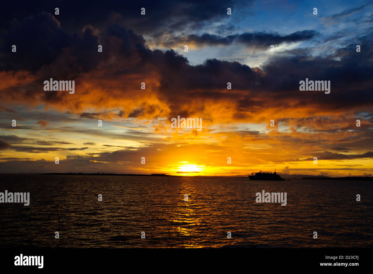 Die untergehende Sonne am flach ruhige Meer in Sorong Raja Ampat West Papua. Boot und Insel Silhouette, warmes Licht. Stockfoto Die untergehende Sonne am flach ruhige Meer in Sorong Raja Ampat West Papua. Boot und Insel Silhouette, warmes Licht. Stockfoto