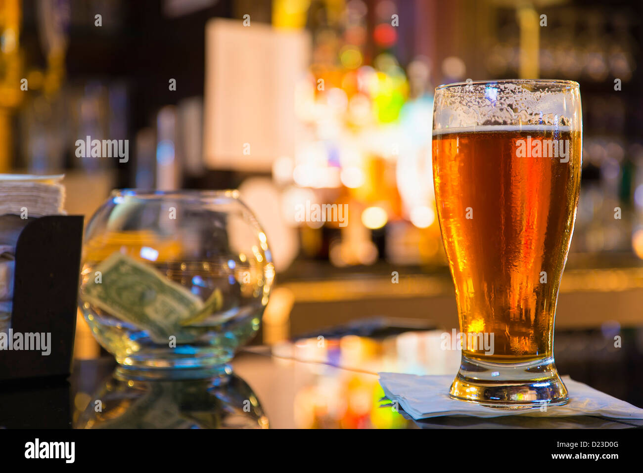 Bernstein frisch gezapftes Bier auf einen Zähler für eine Hotelbar, Tipp-Glas im Hintergrund Stockfoto