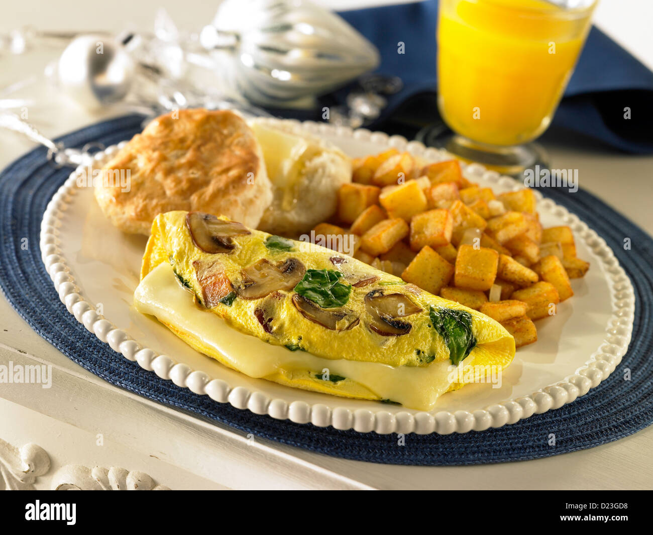 Spinat-Pilz und Käse-Omelette mit Kartoffeln Keks und ein Glas Orangensaft Stockfoto