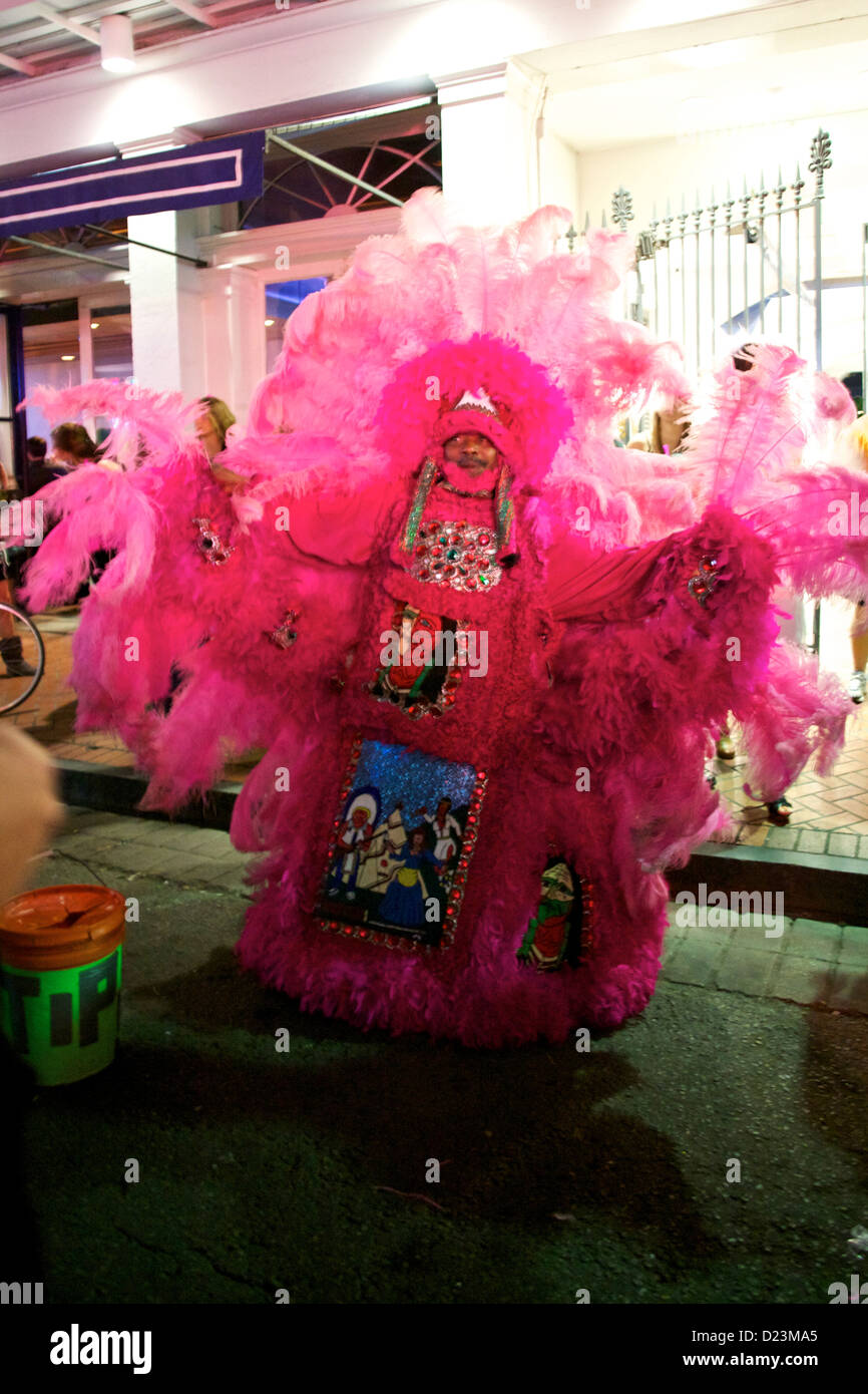 Ein Busker in der Bourbon Street, der ein rosafarbenes Black Masking Indianerkostüm trägt, eine Mardi Gras-Tradition in New Orleans Stockfoto