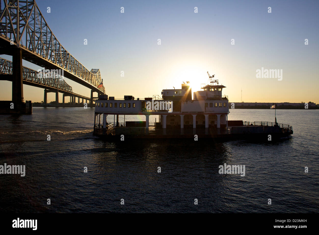 Sonnenuntergang über dem Mississippi River in New Orleans, Louisiana, mit einer Fähre unter der Crescent City Connection Bridge Stockfoto