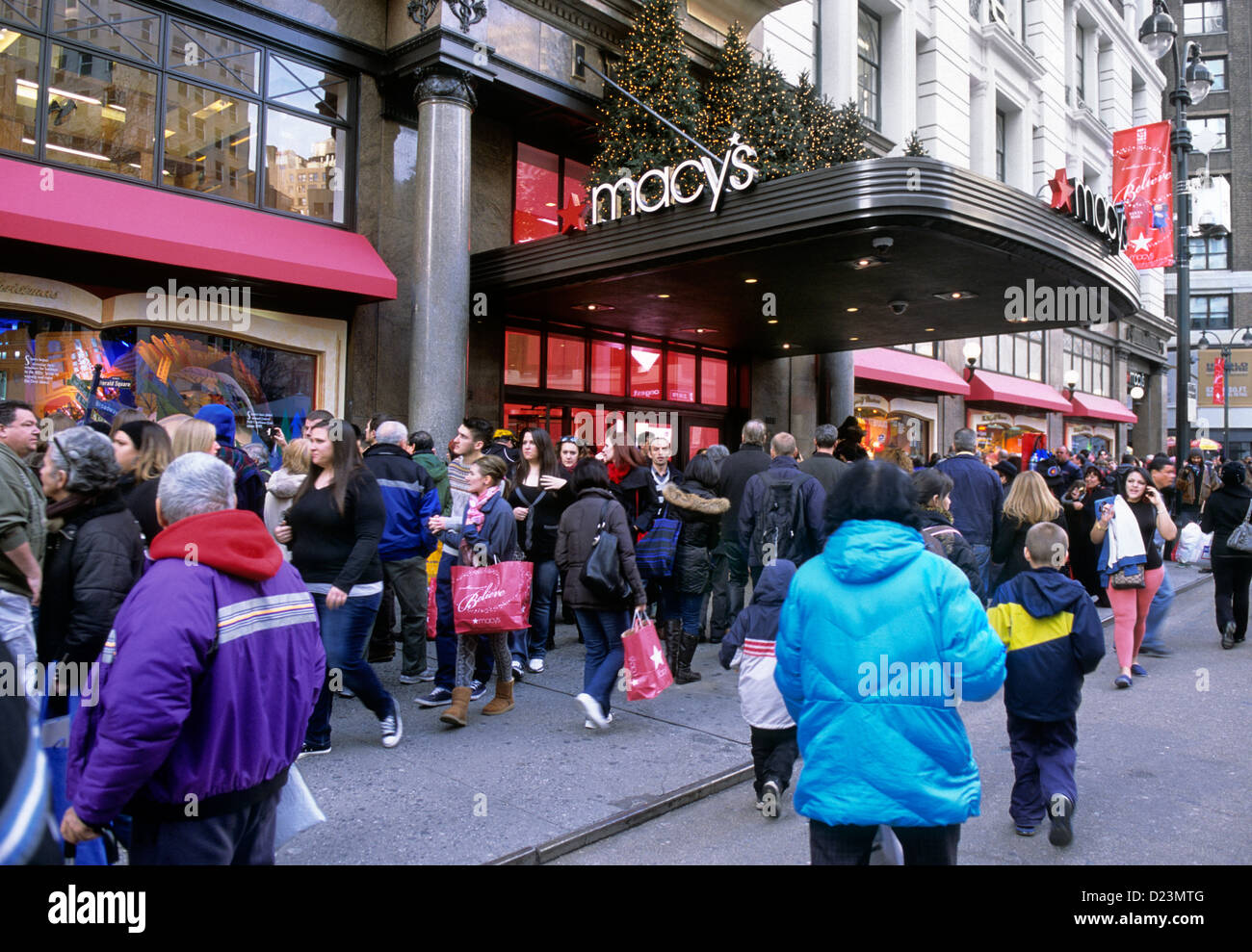 Das Kaufhausgebäude von New York City Macy≥ auf der Straße versammeln sich Menschenmassen, um die Fenster des Weihnachtsfestes zu betrachten. New York, USA Stockfoto