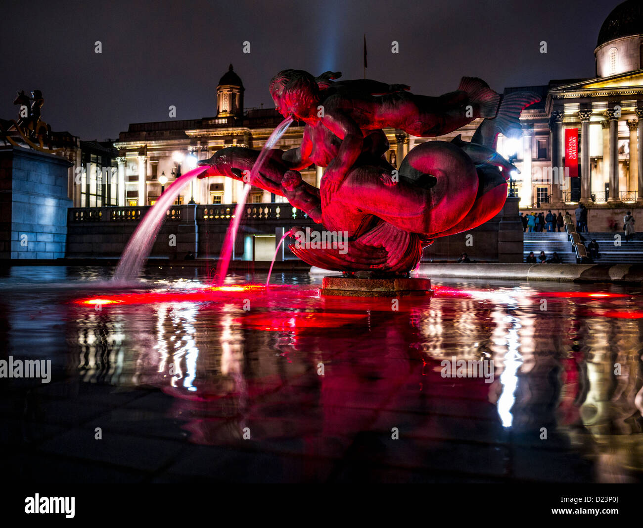 Eine Nachtaufnahme der Wasserbrunnen am Trafalgar Square, die mit rotem Licht beleuchtet wurden, mit der National Portrait Gallery im Hintergrund, 10th. Januar 2013 Stockfoto