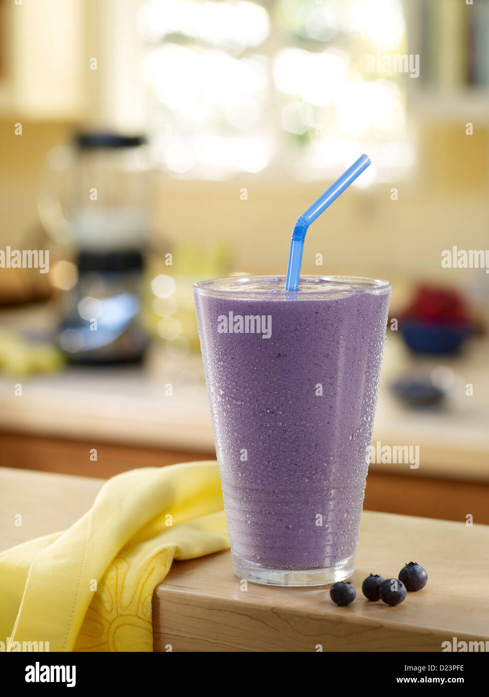 Ein Blueberry Shake inmitten der Küche mit Blender im Hintergrund Stockfoto