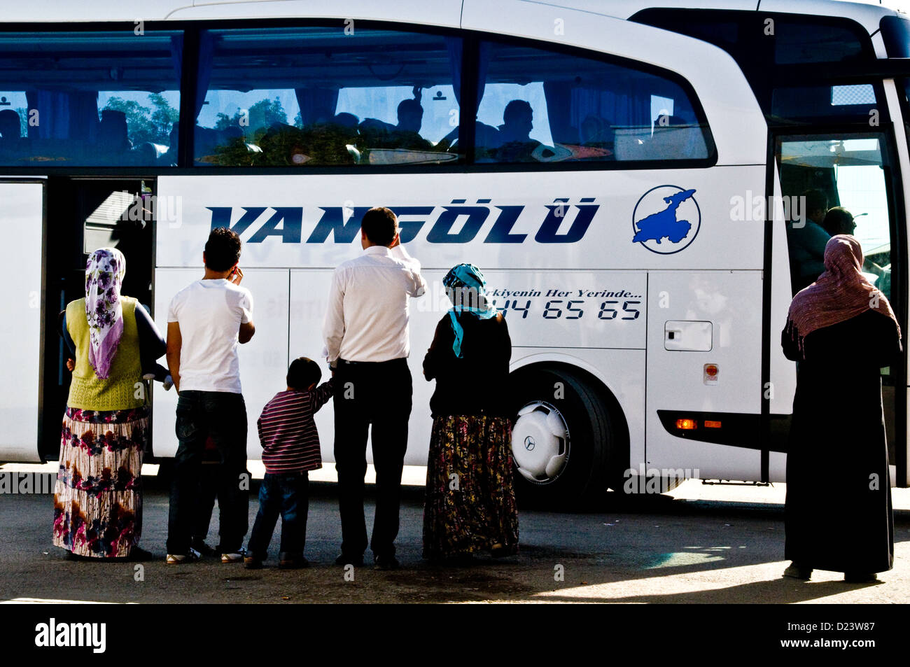Eine kurdische Familie sieht einen Verwandten, der in einem Intercity-Bus am Bahnhof in der Stadt Van in der Region Ostanatolien, Türkei, fährt. Stockfoto