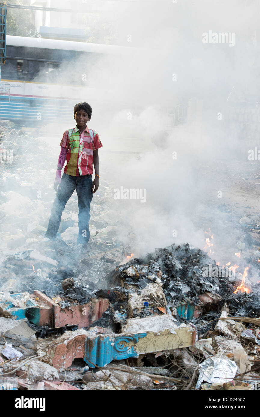 Indischen Jungen stehen unter Verbrennung von Hausmüll entsorgt werden. Andhra Pradesh, Indien Stockfoto