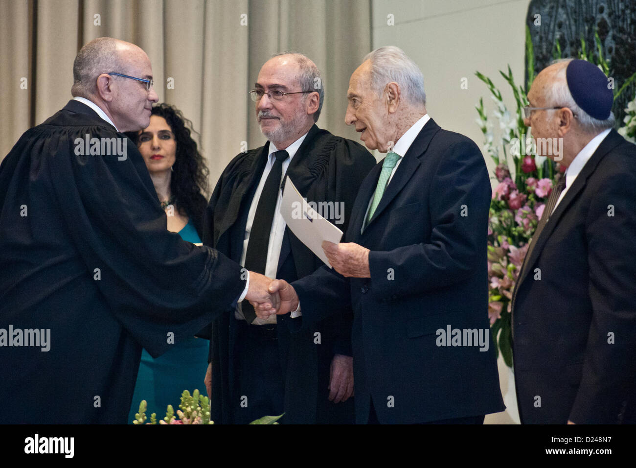 Jerusalem, Israel. 14. Januar 2013. Präsident des Staates Israel, Shimon Peres, schüttelt die Hand befürworten Lior Bringer und übergibt ihm einen Brief der Ernennung zum Amtsgericht Richter im südlichen Stadtteil. Jerusalem, Israel. 14. Januar 2013.  Präsident Shimon Peres gewährt Ernennungsschreiben zwölf neue Richter am Presidents Residenz im Beisein von Justizminister Ya'akov Ne'eman und Honorable Asher Grunis, Präsident des Obersten Gerichts und der High Court of Justice. Stockfoto