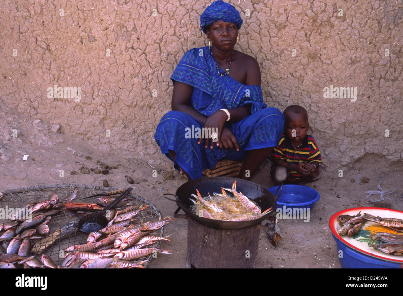 Eine Frau verkauft frisch gekochte Fisch auf einem Markt in Mali, Westafrika. Sie trägt einen Boubou - traditionellen Gewand Kleid. Stockfoto