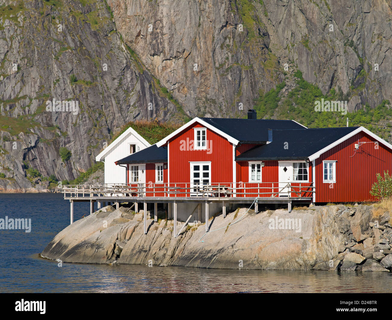 Kabinen und Storeshouses am Ufer des Hamnoya unter den Gipfeln des Festhellstinden und Lilandstinden, Lofoten, arktische Norwegen Stockfoto