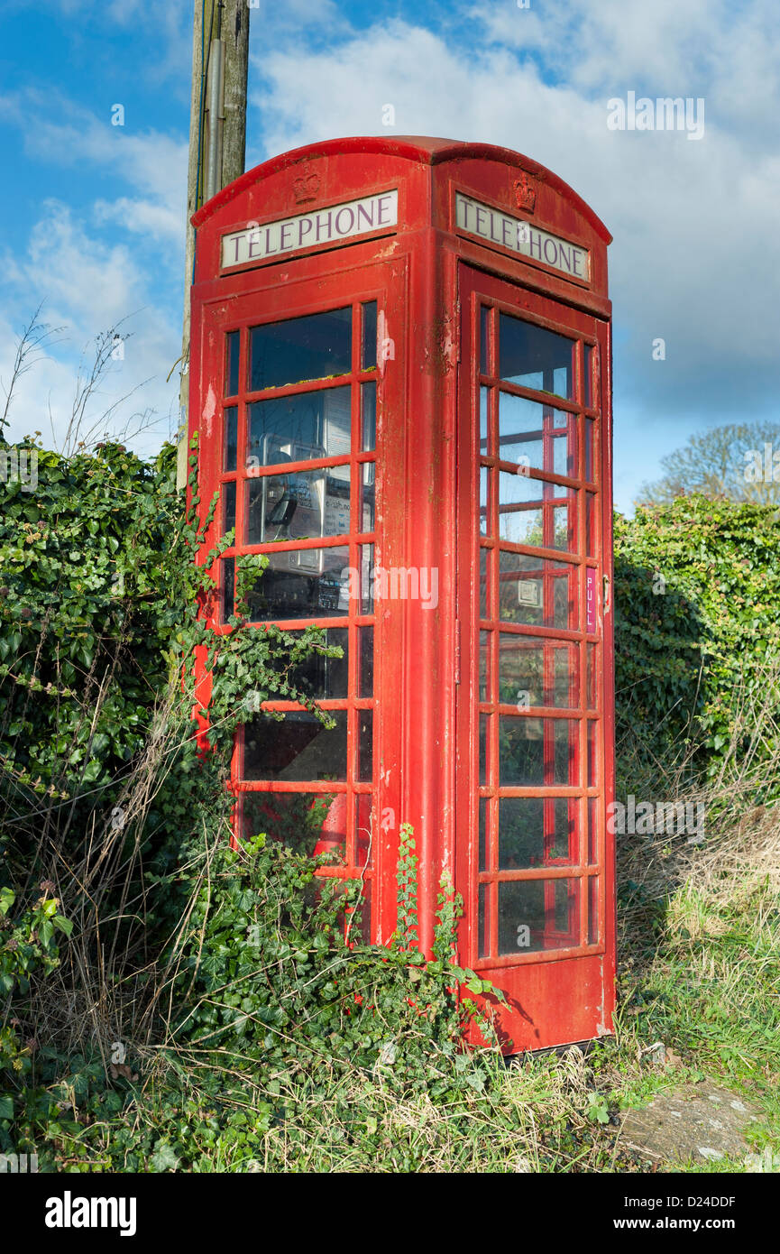 Ungepflegt, überwuchert, rot, BT-Telefonzelle mit angrenzenden Briefkasten Stockfoto
