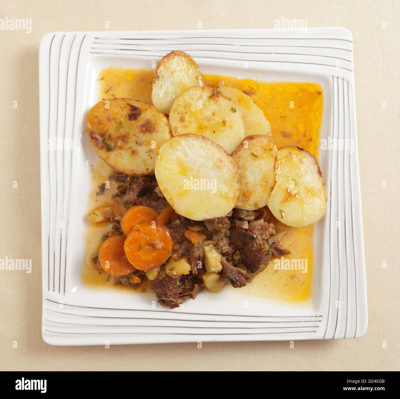 Ein hausgemachter Eintopf aus Rindfleisch, Zwiebeln, Karotten und  Pastinaken, machte in einem Dampfkochtopf, serviert mit Sautierte Kartoffeln  in Scheiben Stockfotografie - Alamy