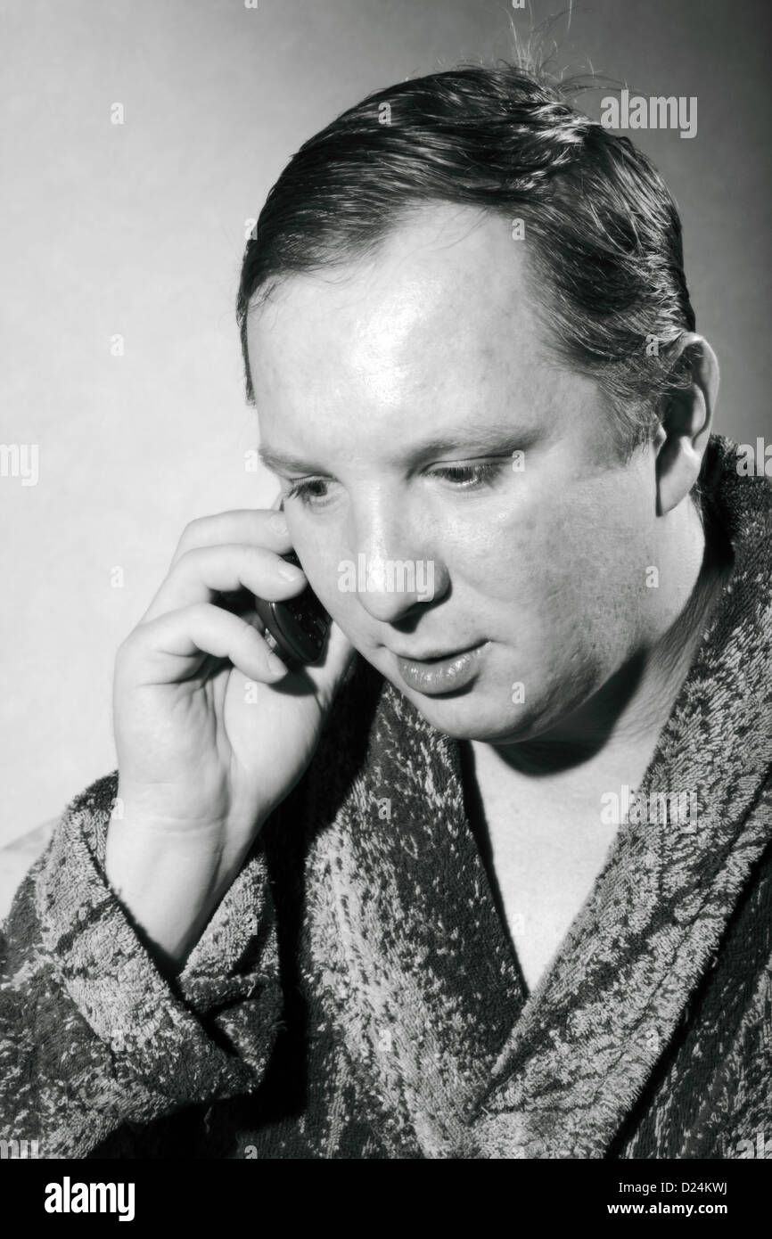 junger Mann im Bademantel auf einem Handy zu sprechen Stockfoto