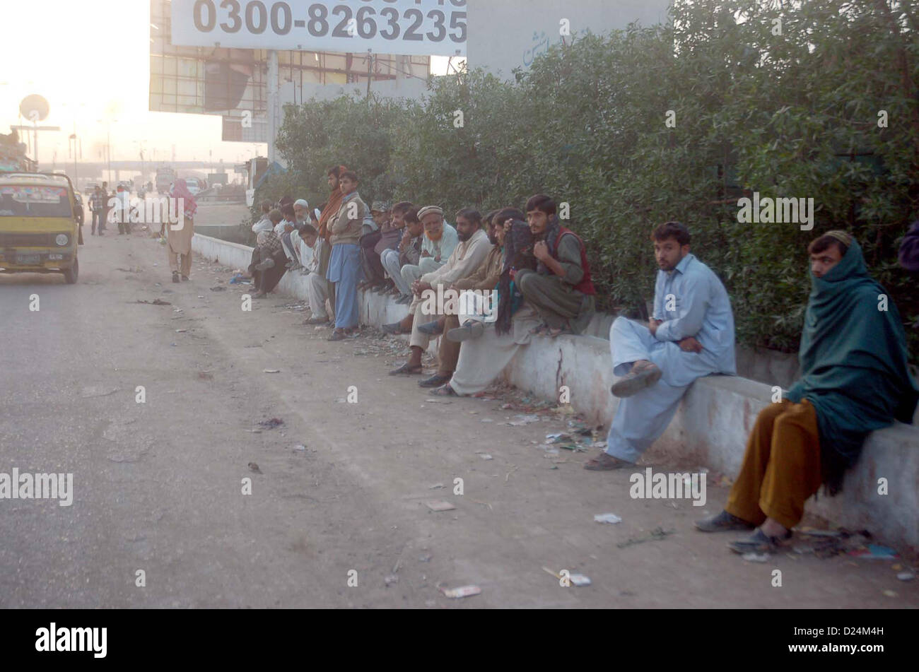 Wartenden für Linienbusse wie der Mangel an Verkehr während der Streik von schiitischen Ulema Rat gegen die Tötung von schiitischen Moslems und Völkermord der schiitischen Hazara Gemeinschaft in Pakistan, am Shahrah-e-Faisal in Karachi auf Montag, 14. Januar 2013 eingehalten wird. Stockfoto