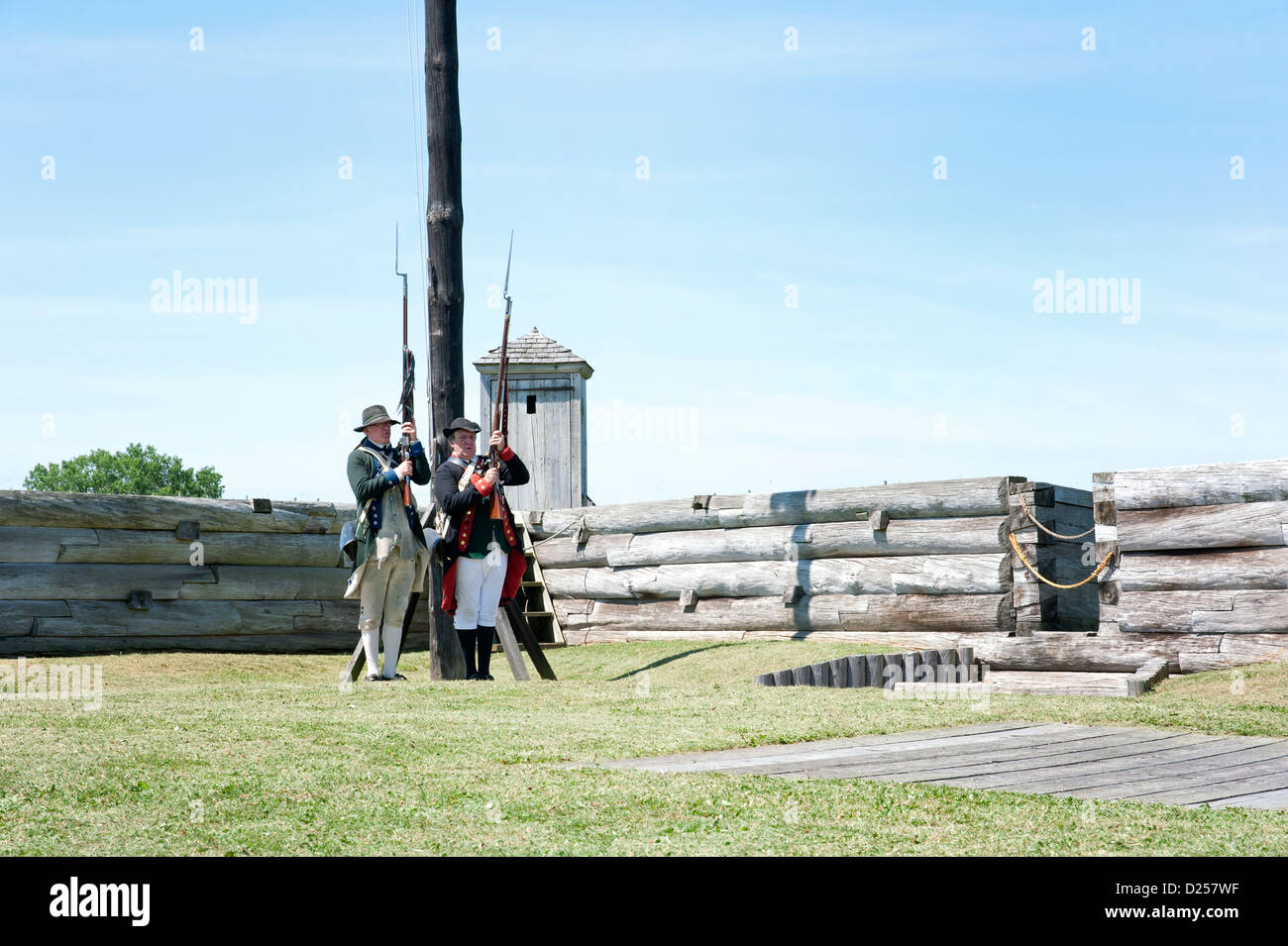 Fort Stanwix Reenactors: American Continental Artillery Soldaten halten Muskete hinter Kastellmauern. Stockfoto