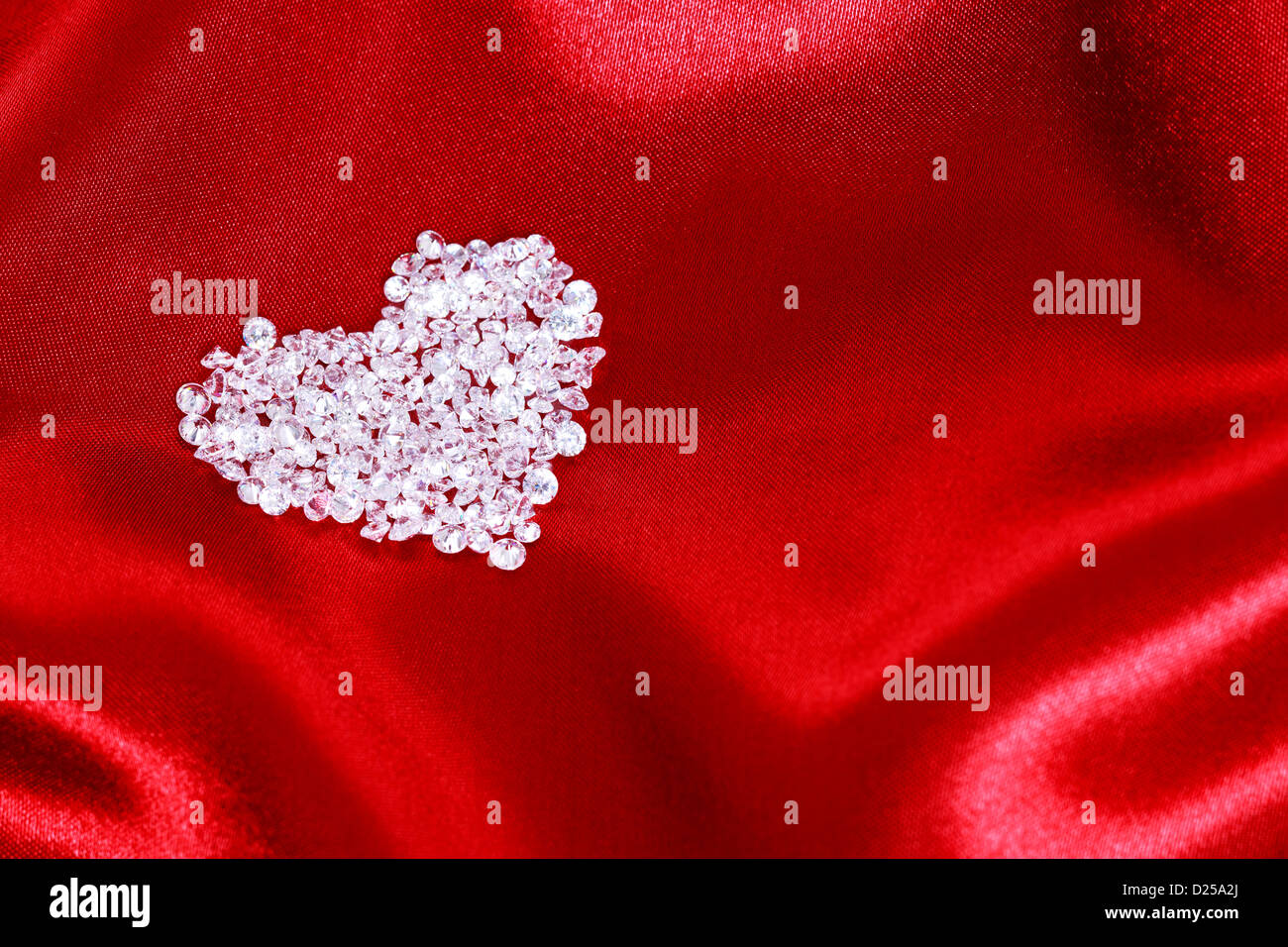 Herzform aus CZ Diamanten auf rotem satin gefertigt. Stockfoto
