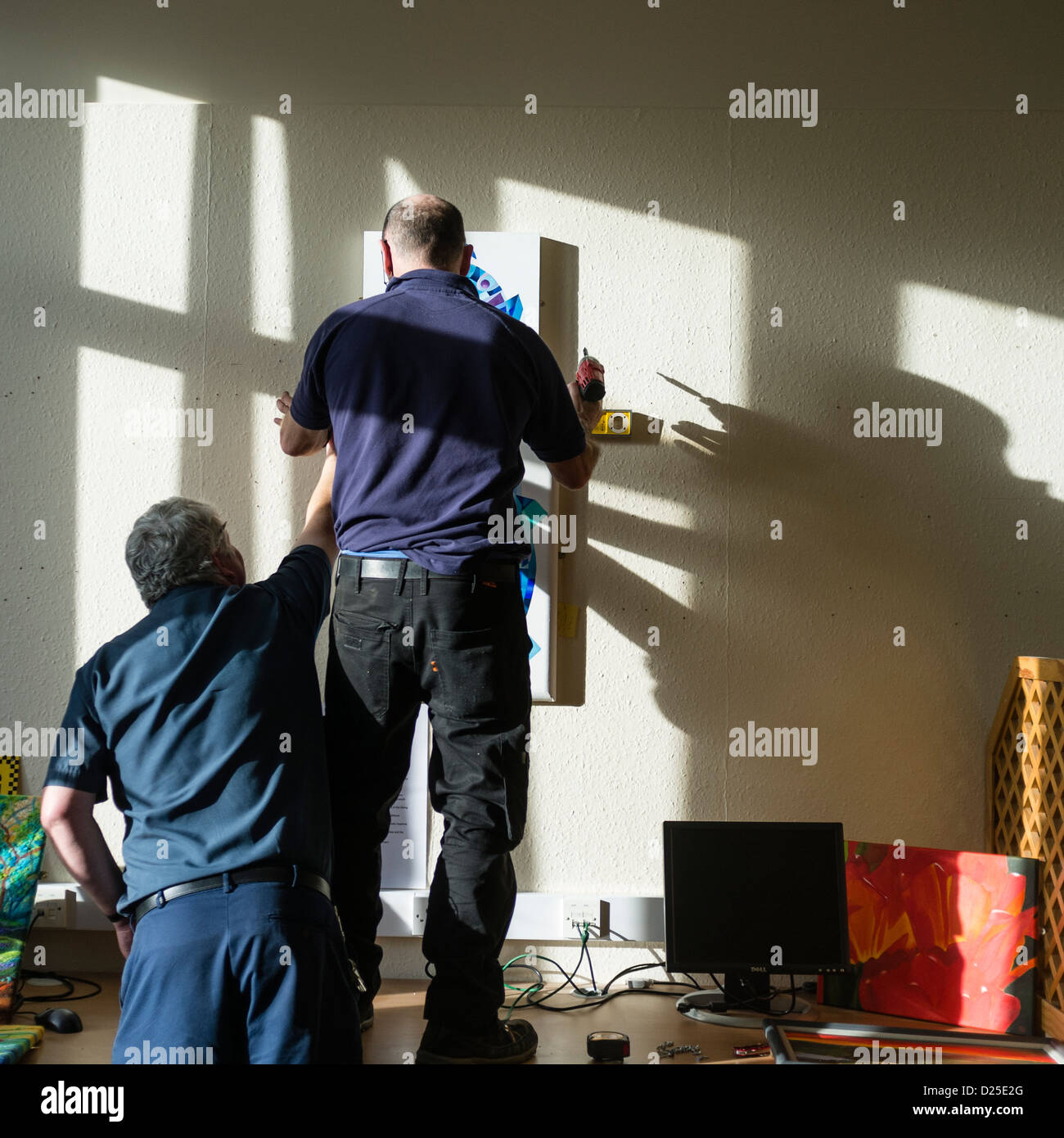 Zwei Arbeiter, die Installation einer Kunstausstellung am Bronglais General Hospital, Aberystwyth Wales UK Stockfoto