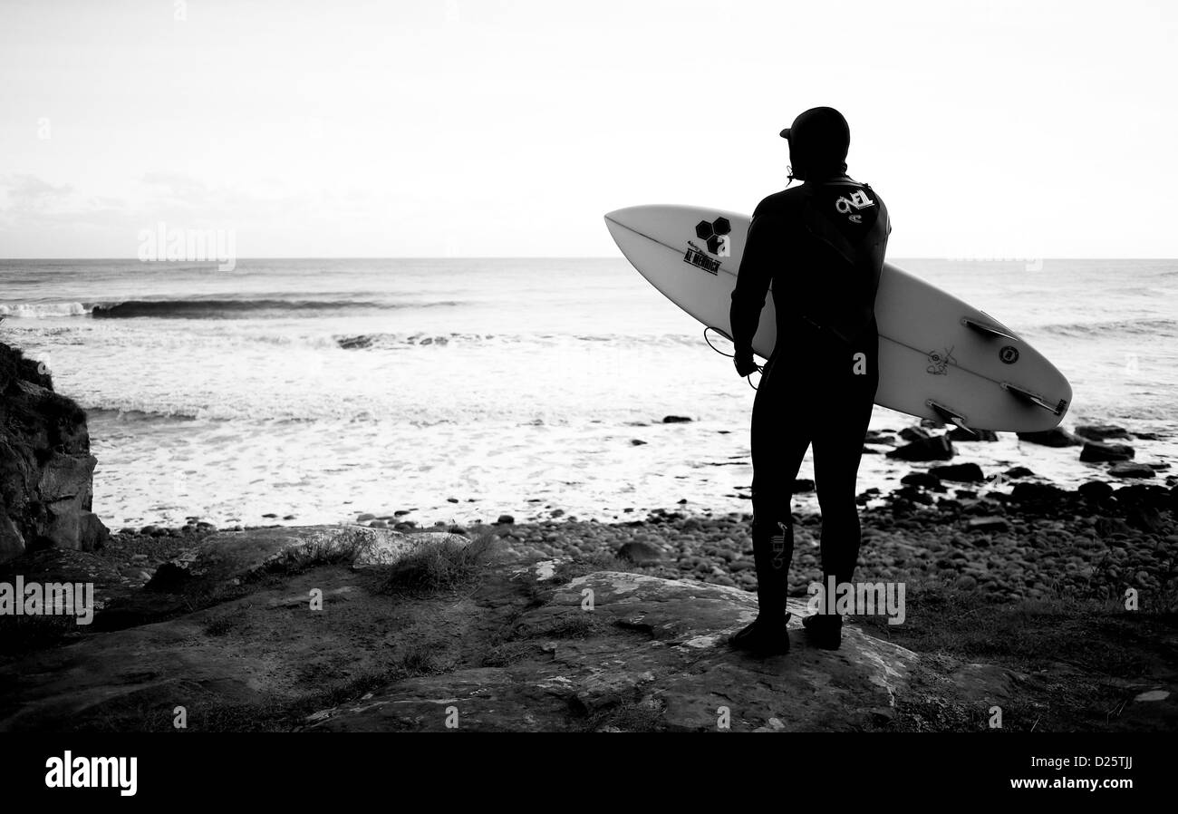 Eine Surfer schaut zu, wie Wellen bei einem Surfen vor Ort in Yorkshire an der Nordostküste Englands brechen. Stockfoto