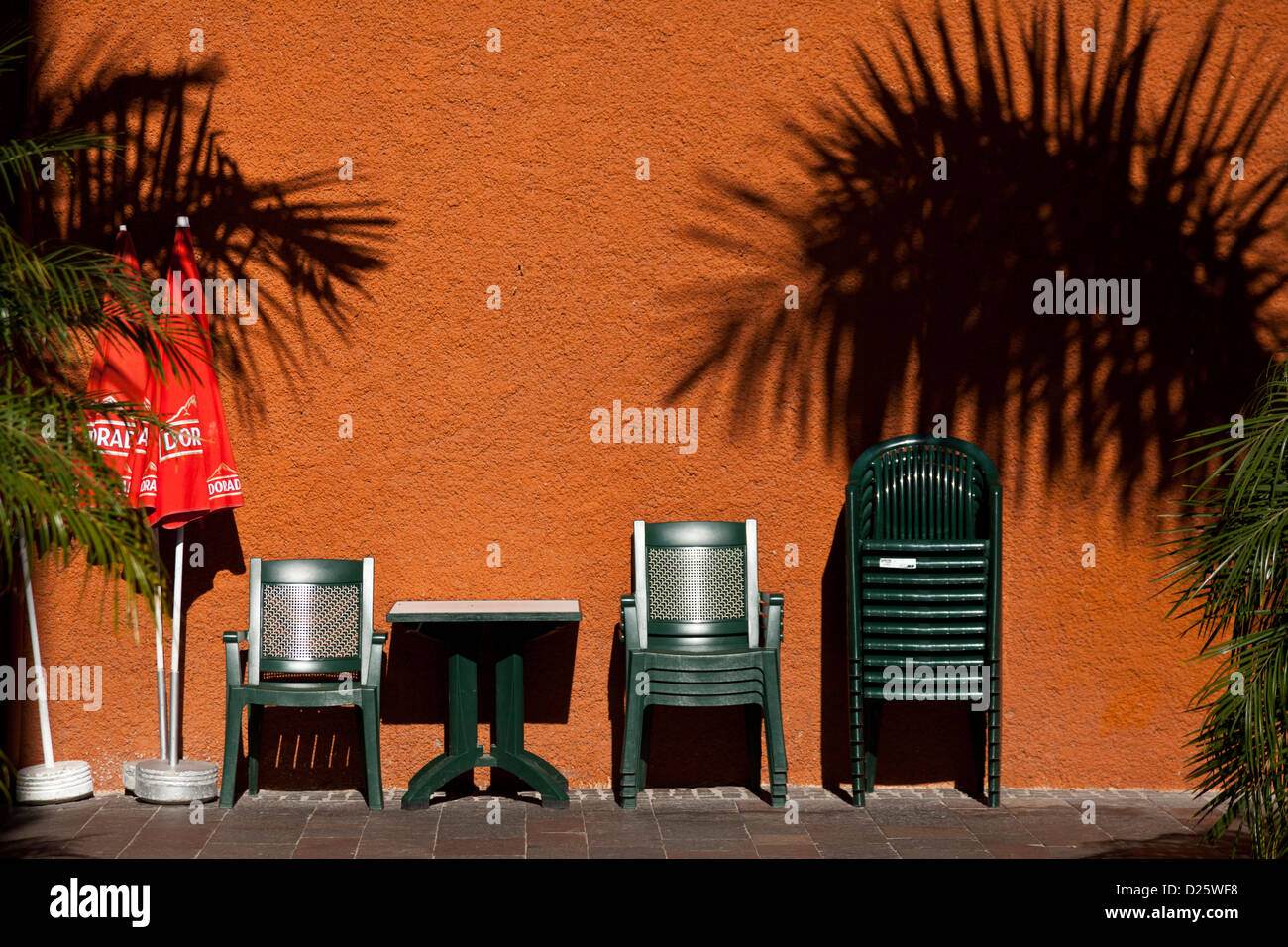 Kunststoff-Café Möbel aufgetürmt eine orange Wand auf der Straße in Los Cristianos, Teneriffa, Kanarische Inseln, Spanien Stockfoto