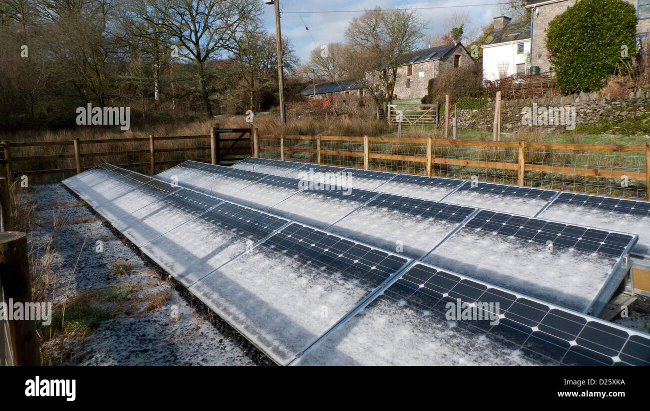 Schneerauf auf bodenmontierten Solarpaneelen und Steinhütten-Scheunen im Winter auf einem Kleinbetrieb in West Wales, Großbritannien KATHY DEWITT Stockfoto