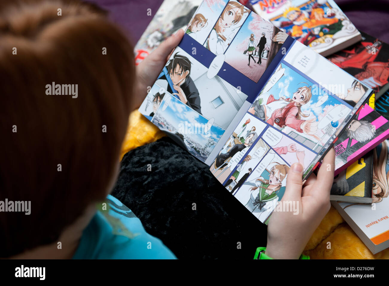 Eine Youg Teenager-Mädchen ist eine Manga-Buch lesen. Stockfoto