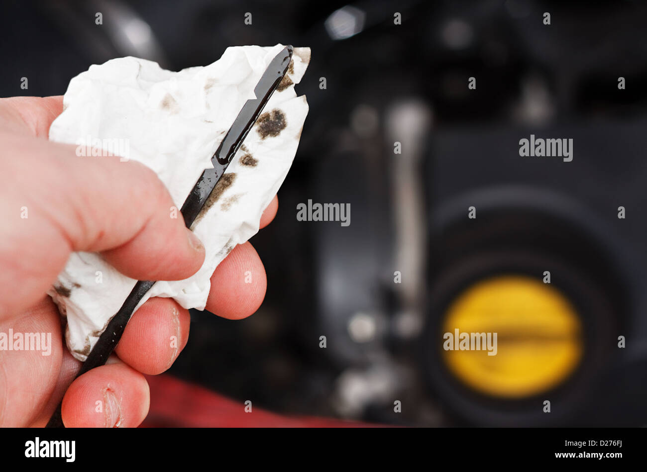 Überprüfung der Motorölstand auf ein Auto Messstab während seiner regelmäßigen Service, Öldeckel und Motor im Hintergrund Stockfoto