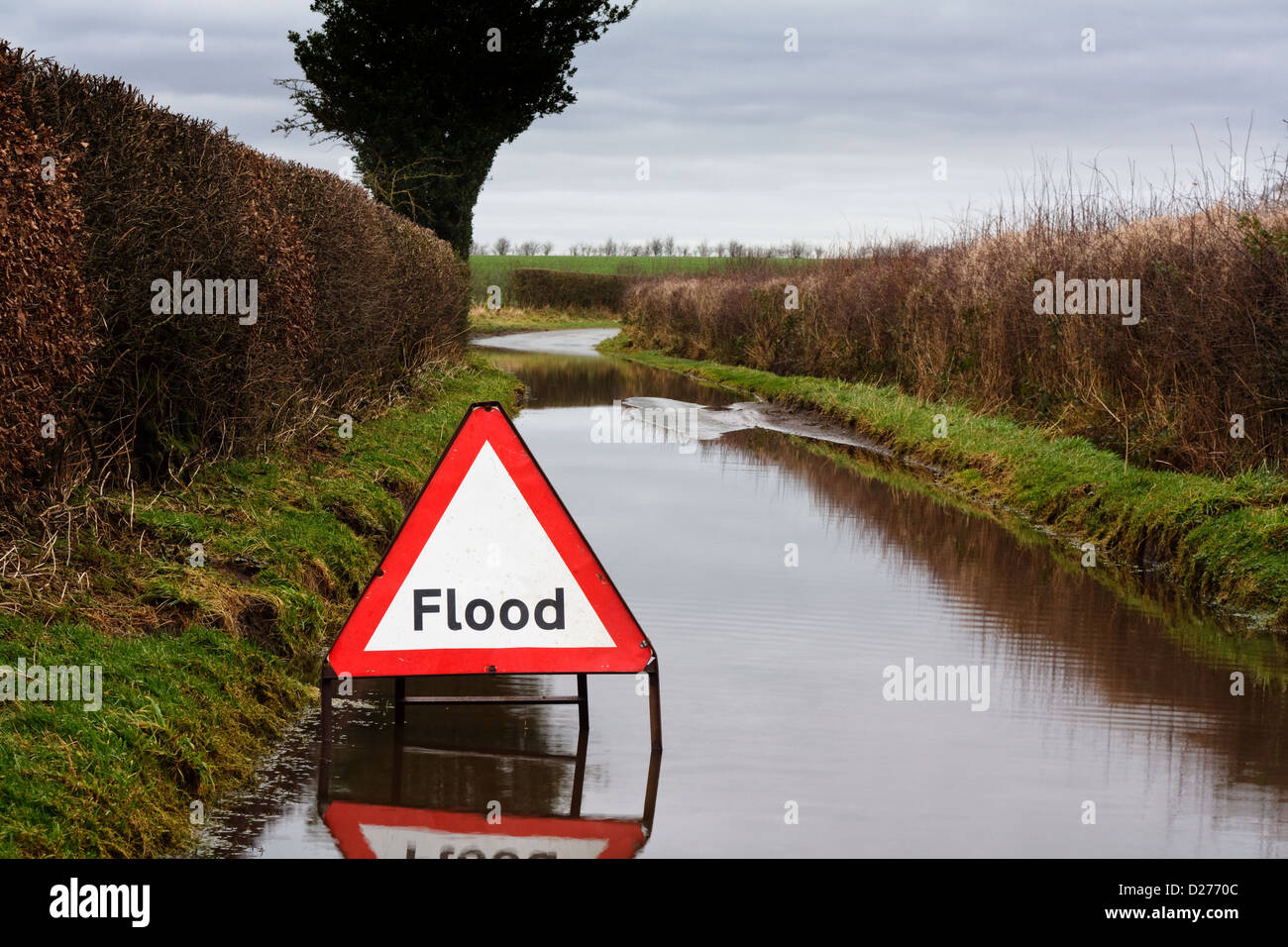 Flut-Warnschild auf einer überfluteten Landstraße mit ungünstigen Fahrbedingungen Stockfoto