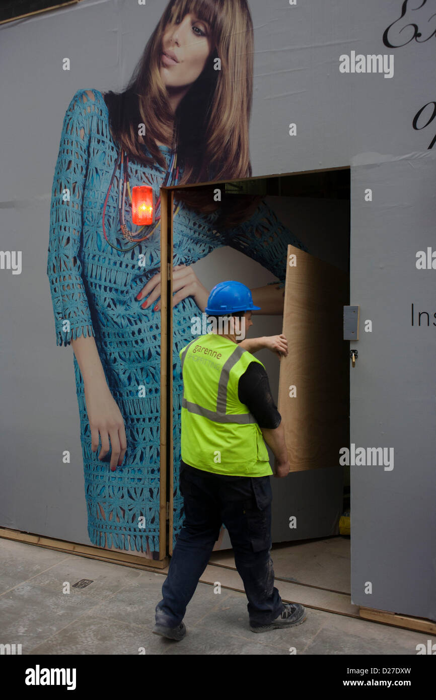Arbeiter trägt Ply-Plattenwerkstoffen auf Website unter Mädchenmode horten. Stockfoto
